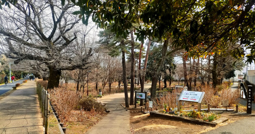 「あじさい公園」の看板が立つ、冬の公園入口。葉を落とした木々が見える。